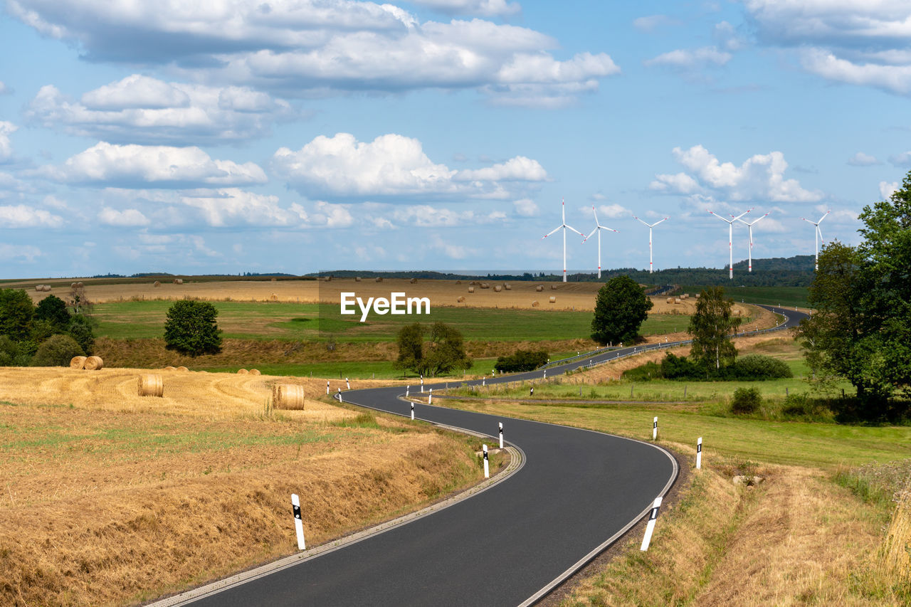 Road amidst field against sky