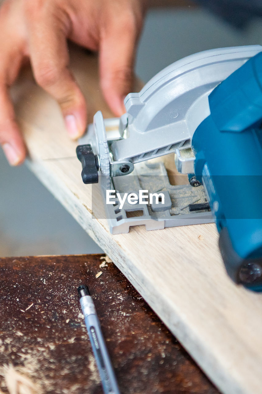 Close-up of a carpenter using a circular saw to cut a plank of wood