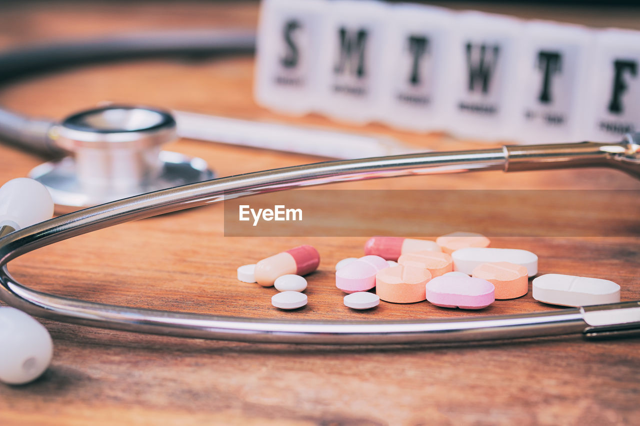 High angle view of medicines with medical equipment on wooden table