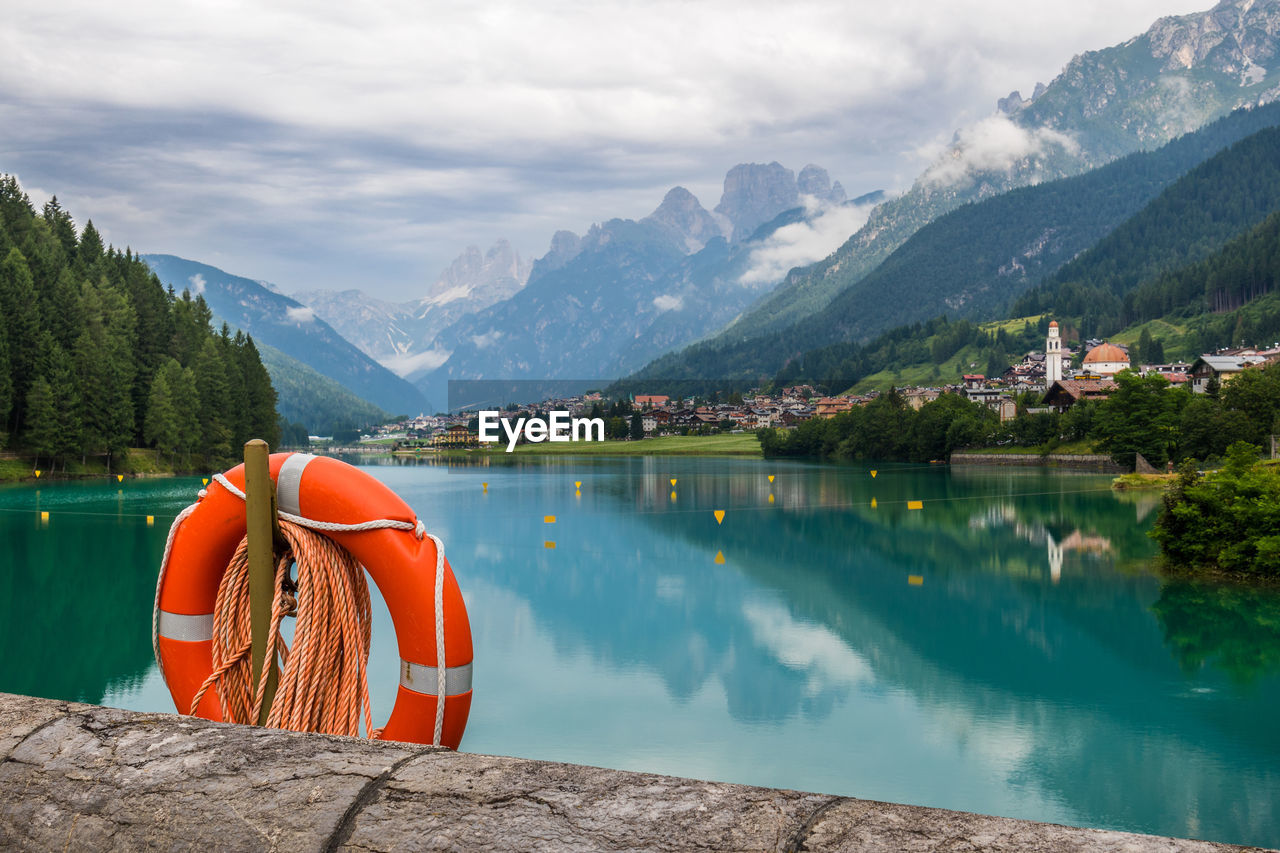 Life belt hanging by lake by mountains against sky