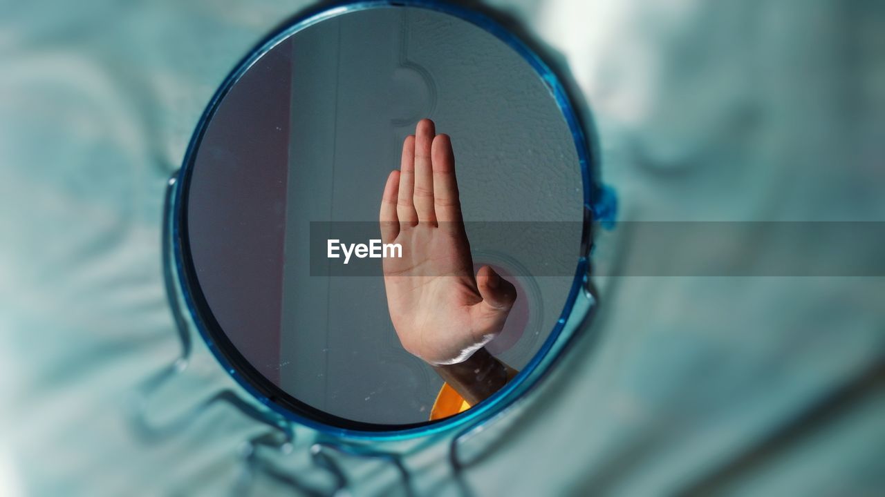 Reflection of man showing stop gesture on mirror