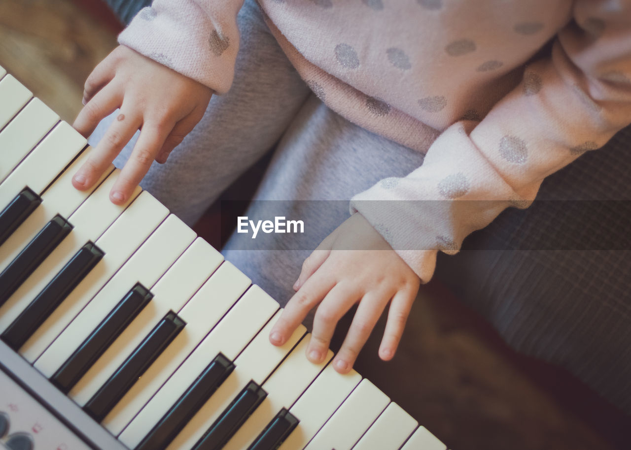 A little girl plays the electric piano.