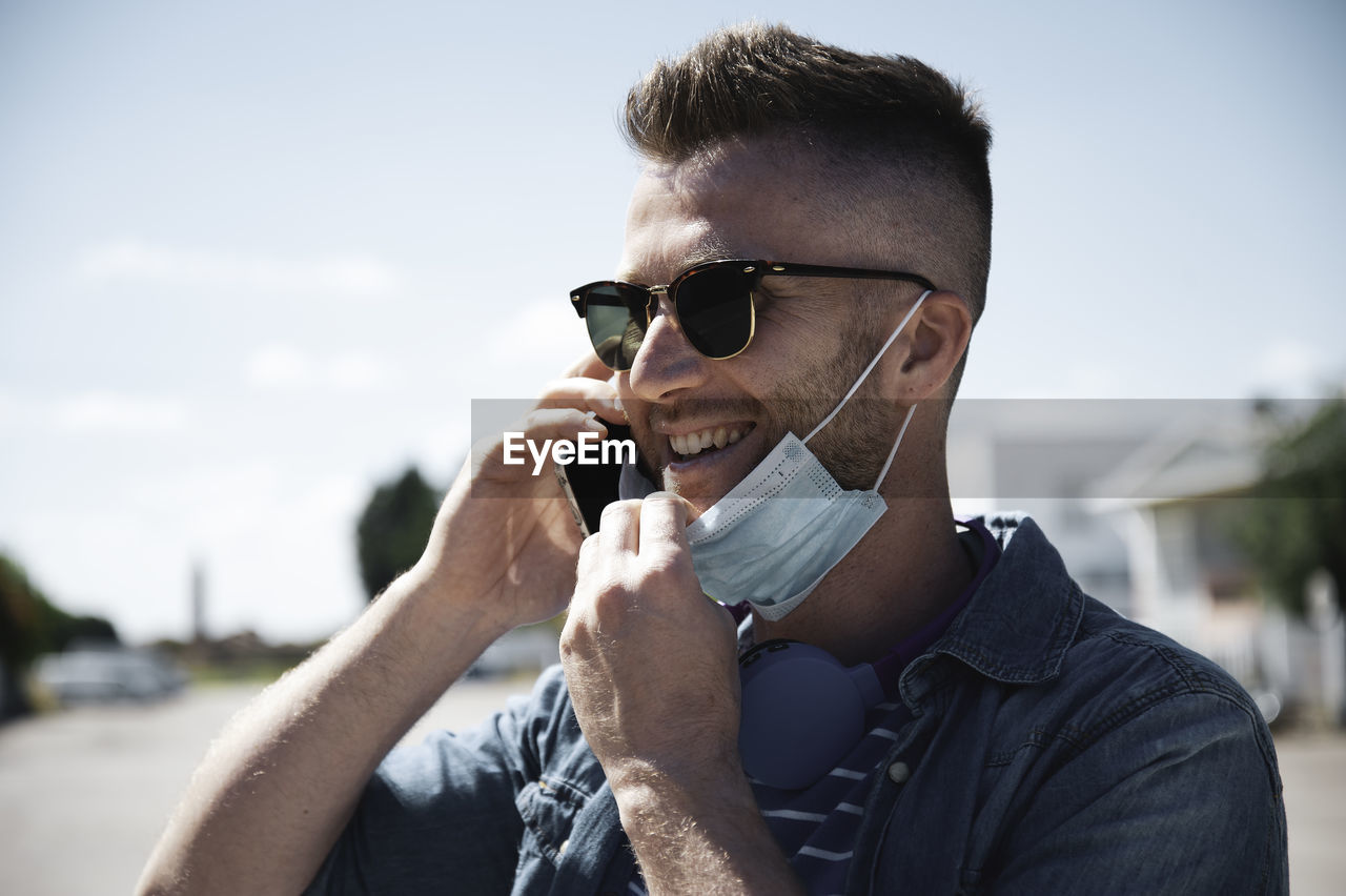 PORTRAIT OF YOUNG MAN WEARING SUNGLASSES AGAINST SKY