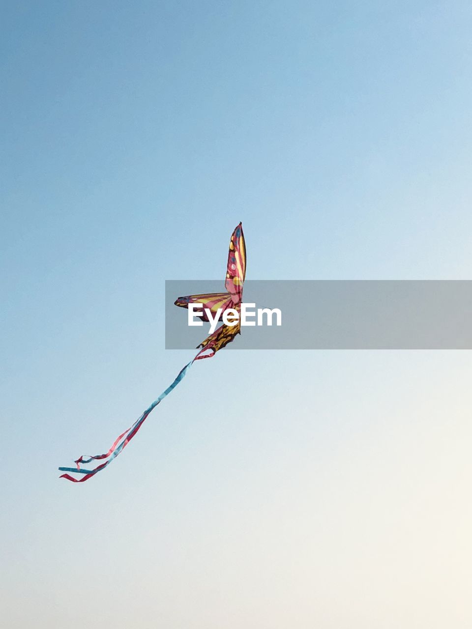 LOW ANGLE VIEW OF KITE FLYING AGAINST CLEAR SKY