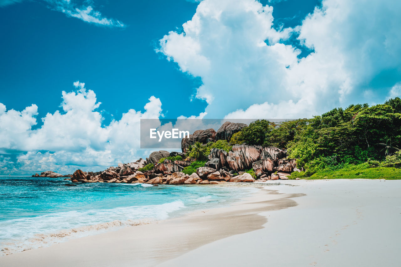 Grand anse exotic beach at la digue island, seychelles. white sand, blue ocean, waves, granite rocks