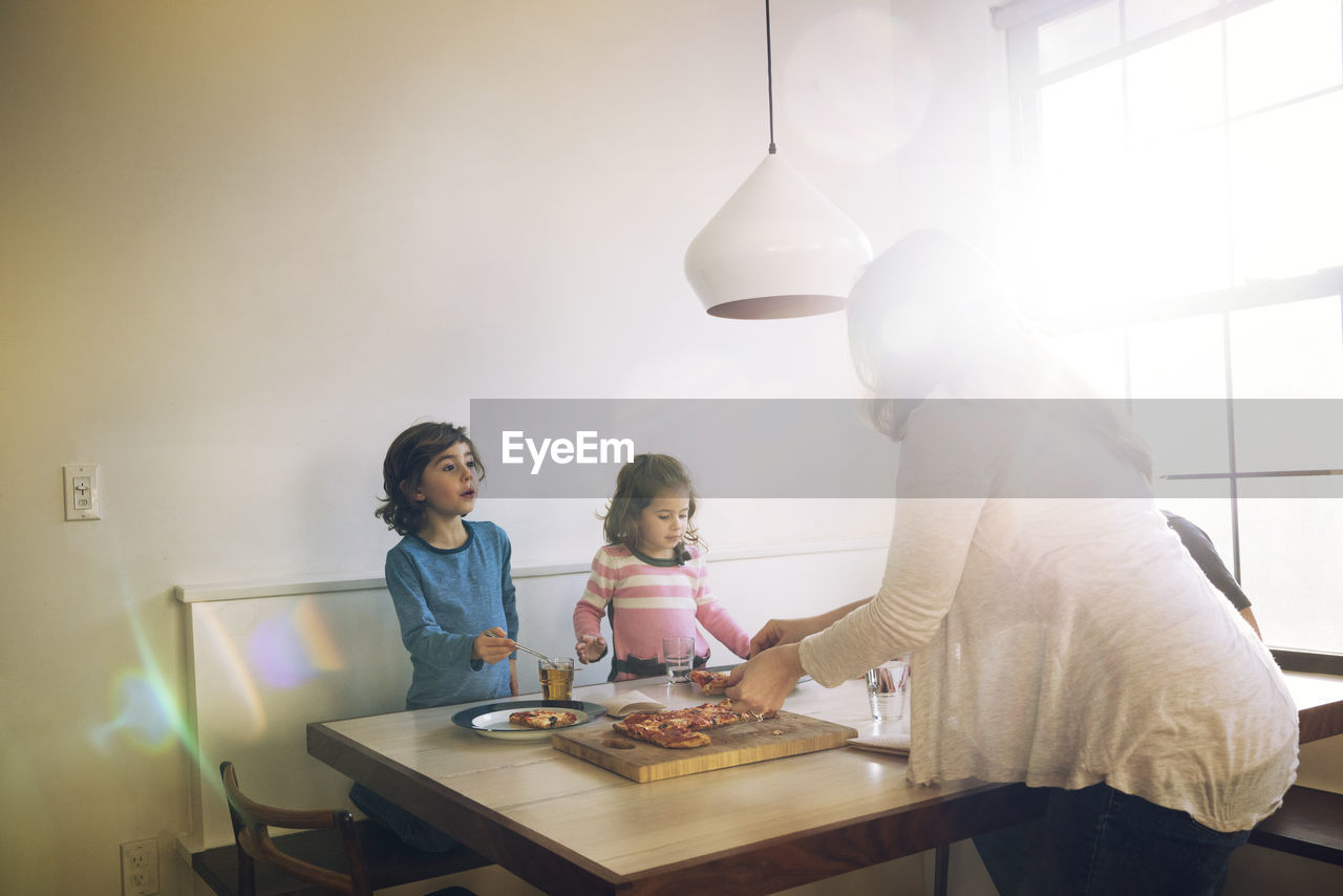 Family eating pizza at dining table in home