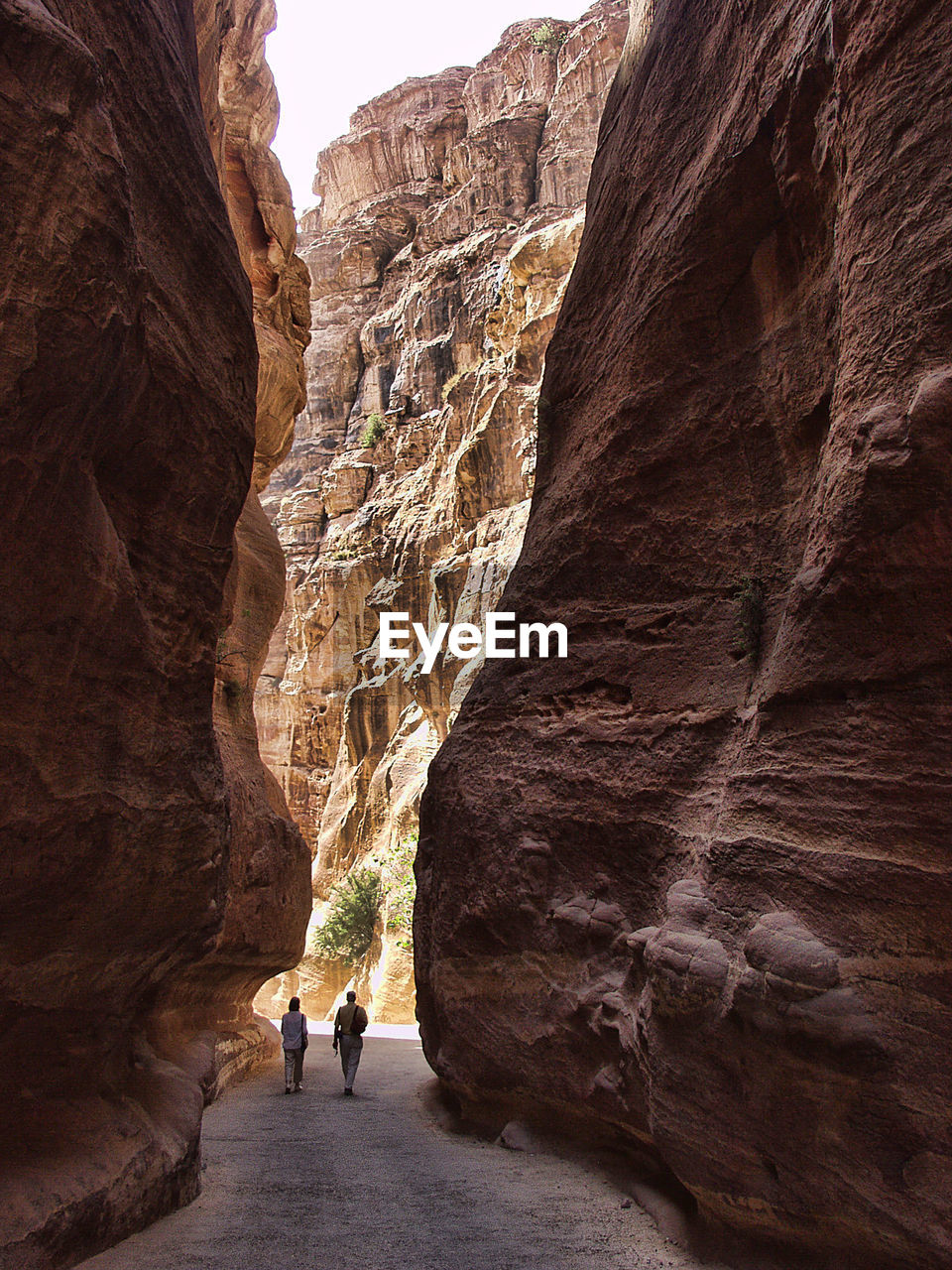 Rear view of people walking amidst rock formations