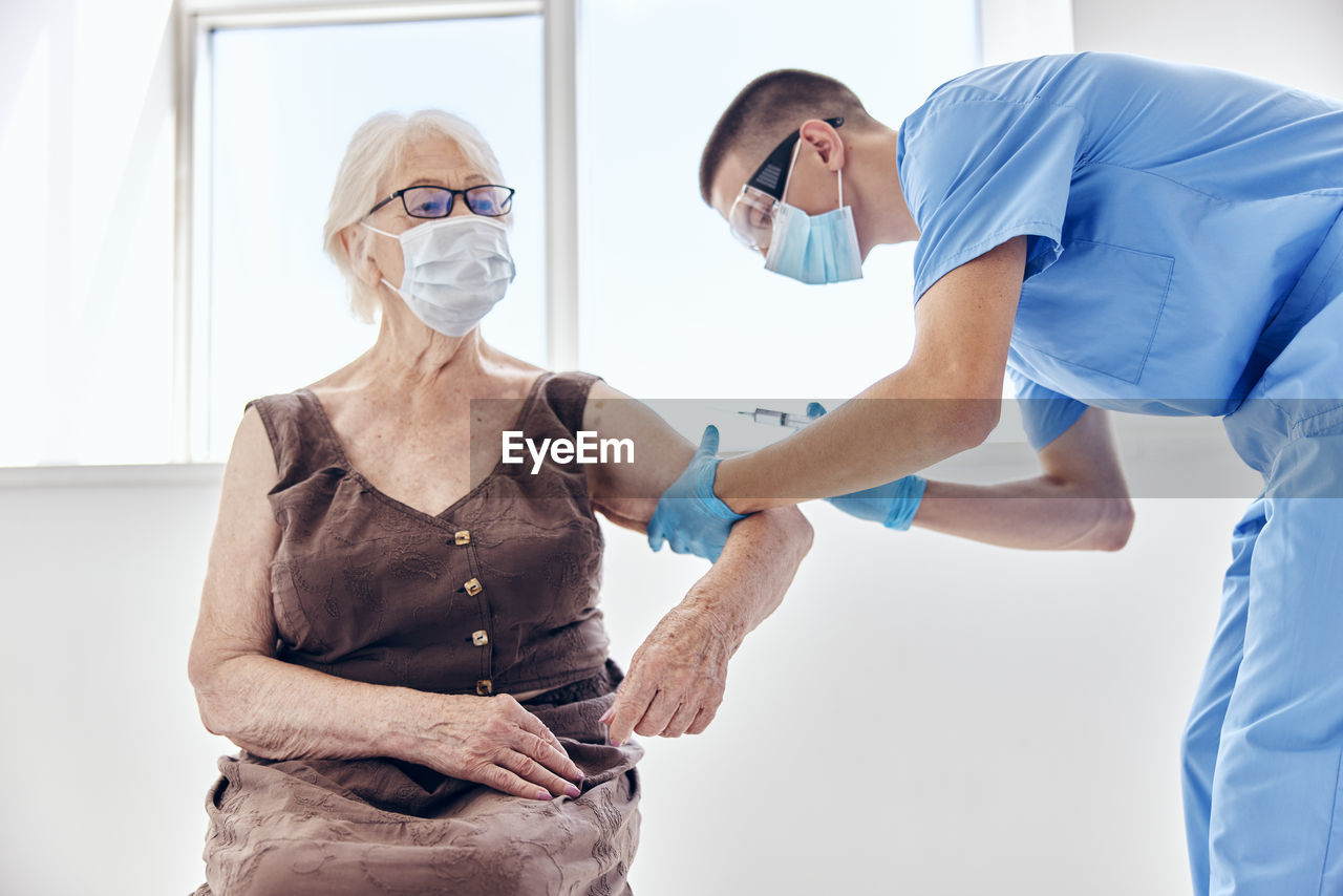 Doctor wearing mask vaccinating patient