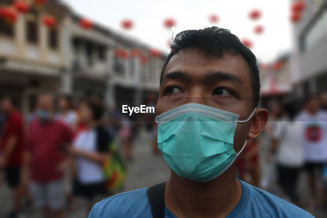 Close-up portrait of a young man with protective mask on a street 