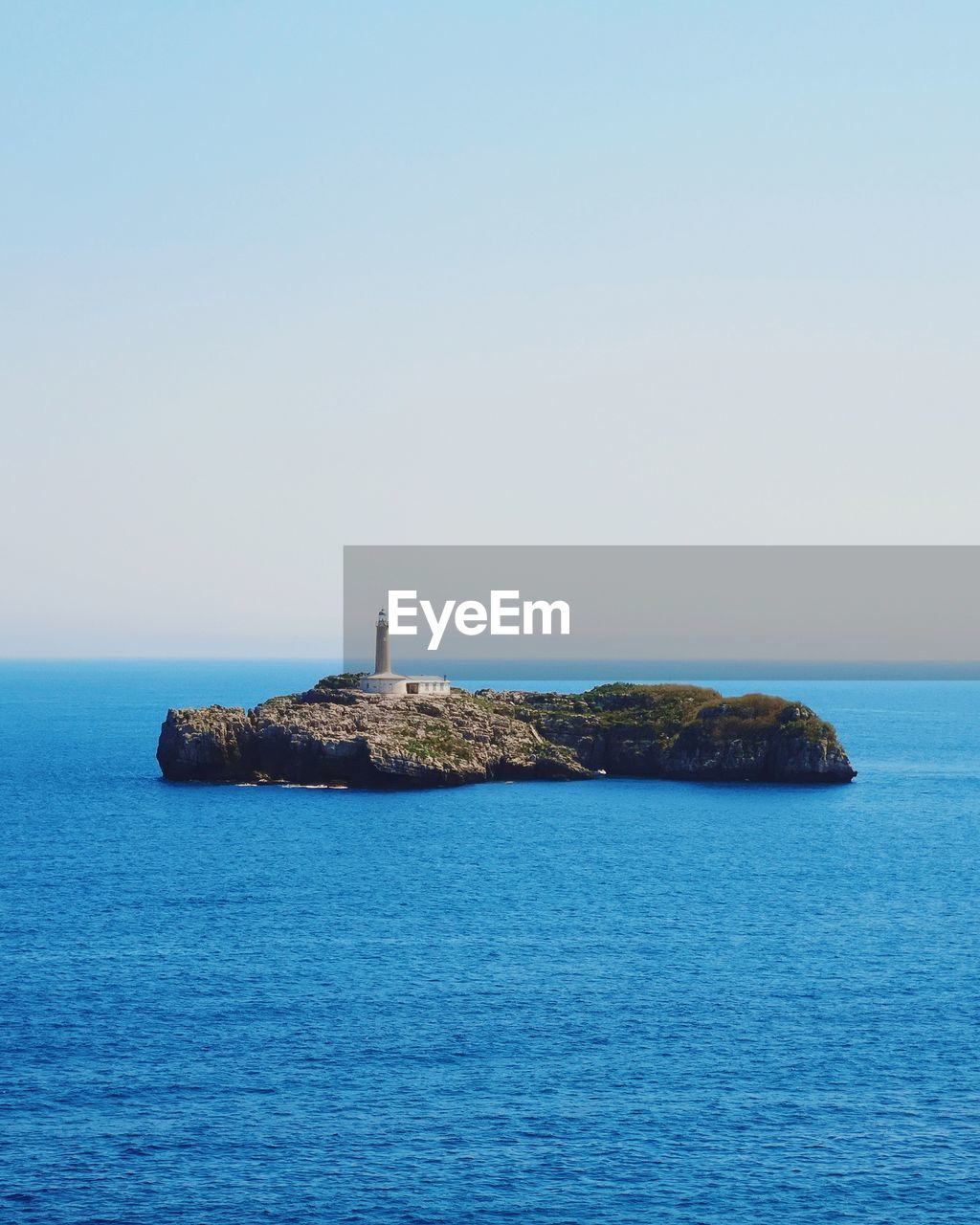 Lighthouse in sea against clear sky