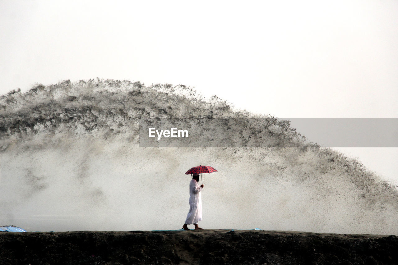 Rear view of a man standing on rainy day