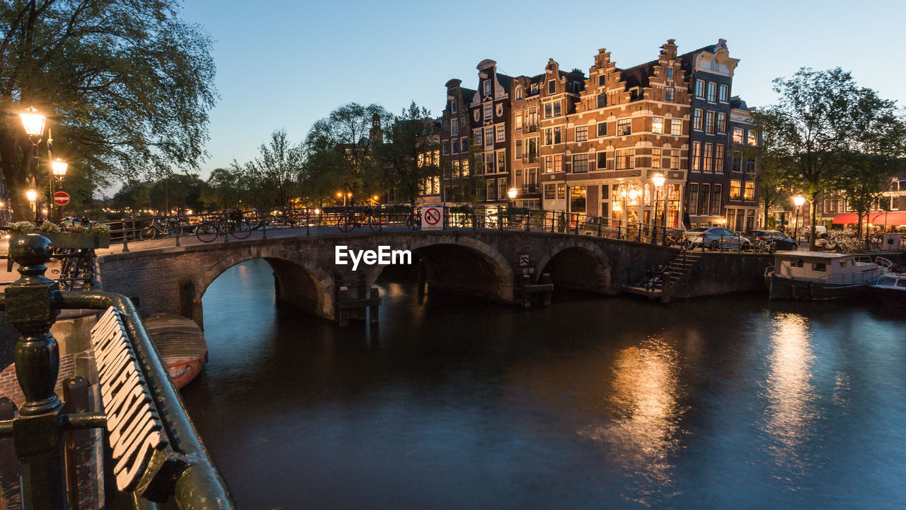 Arch bridge over canal against sky in city