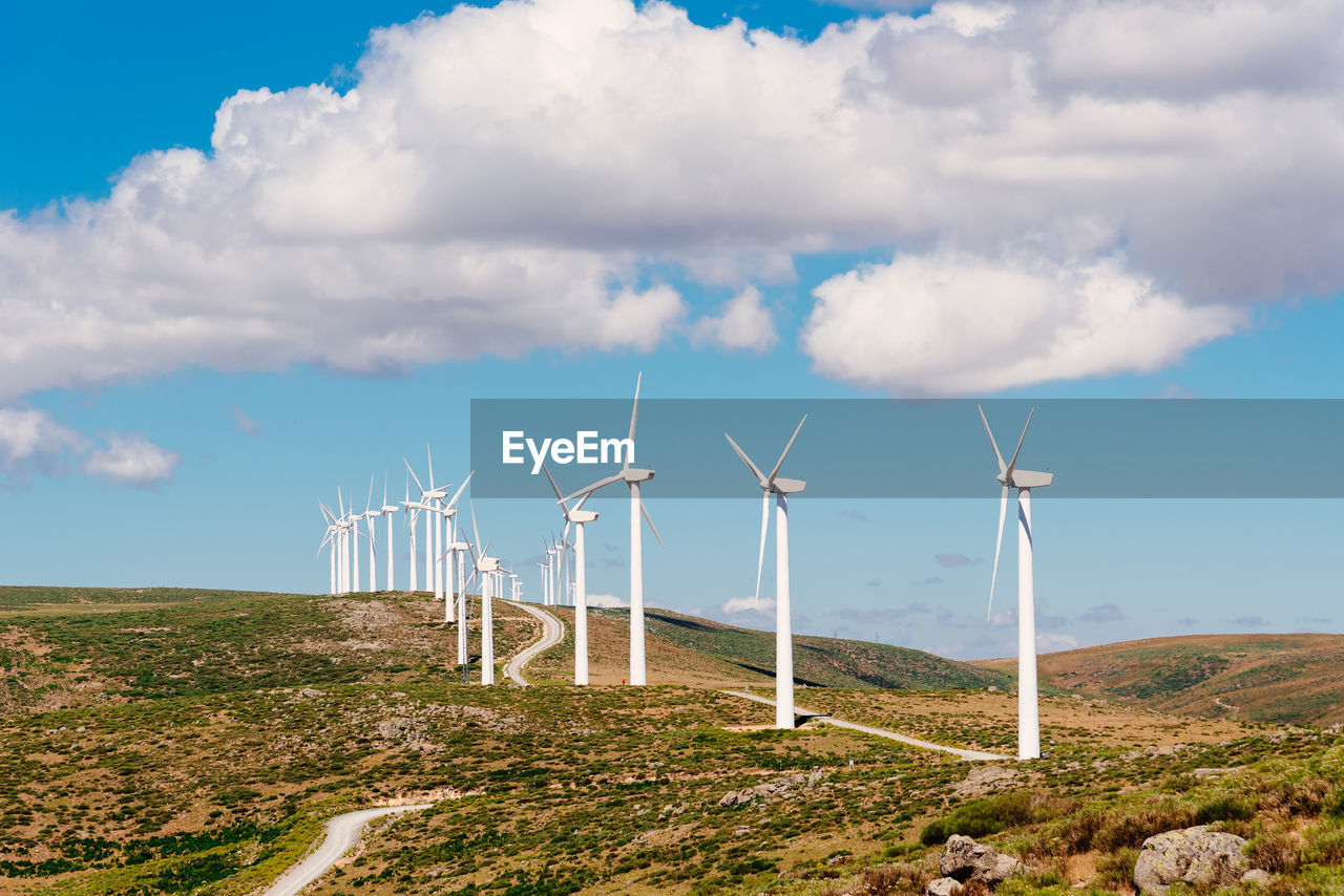 Wind turbines for power generation on hill against blue sky