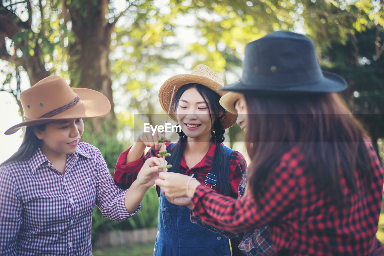 Happy female friends looking at buds while standing at park