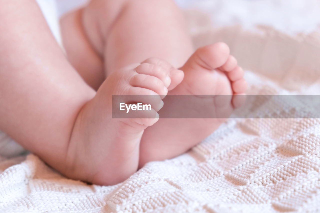 Tiny babies feet on white blanket. close up of small bare feet of baby infant sleeping on soft bed.