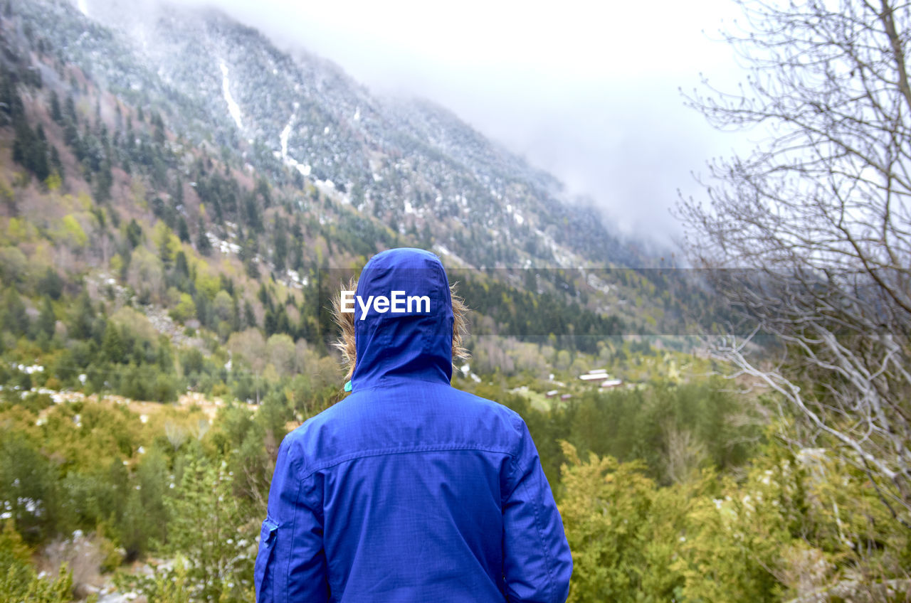 REAR VIEW OF WOMAN LOOKING AT MOUNTAIN