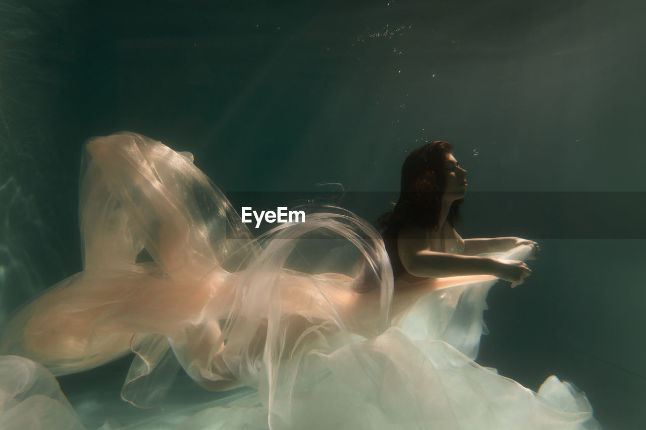 Woman with curtain swimming in pool