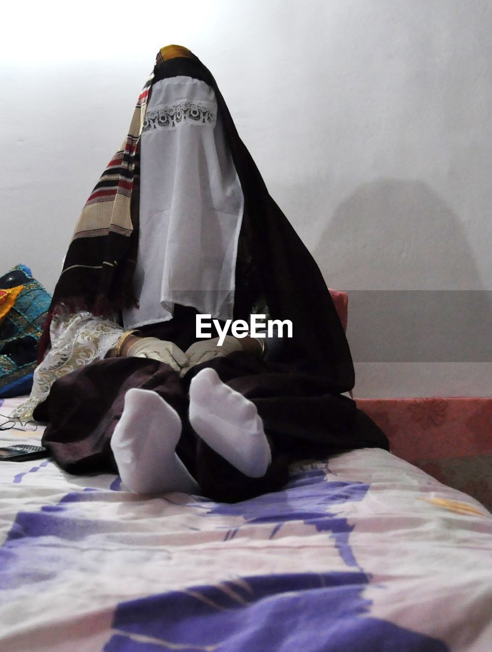 Woman in burka sitting on bed at home