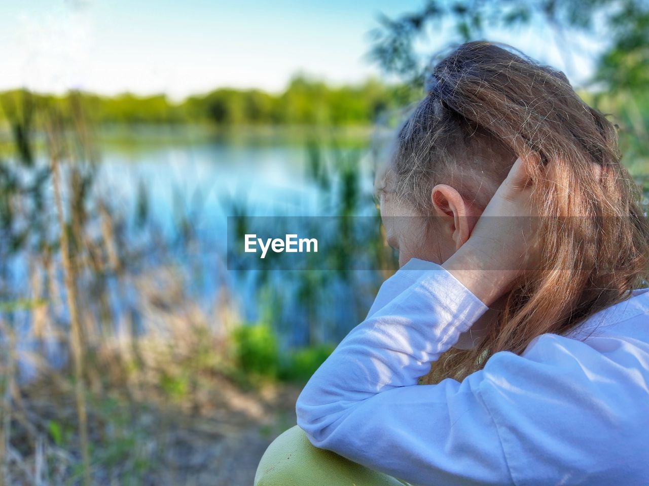 PORTRAIT OF WOMAN SITTING ON LAKE AGAINST PLANTS