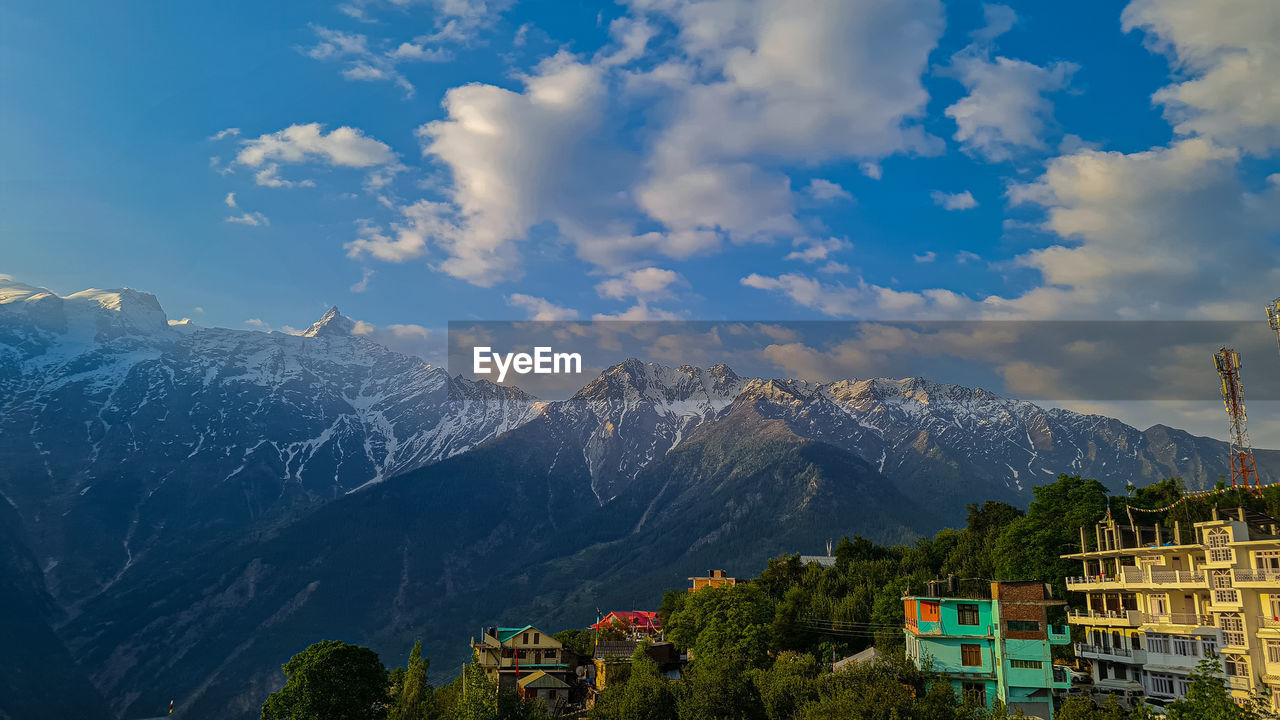 mountain, sky, mountain range, architecture, scenics - nature, cloud, environment, landscape, nature, built structure, beauty in nature, building, building exterior, travel destinations, land, travel, tree, city, house, plant, snow, tourism, no people, mountain peak, blue, outdoors, winter, residential district, forest, snowcapped mountain, village, cold temperature, valley, vacation, trip, holiday, tranquility, morning, pinaceae, pine tree