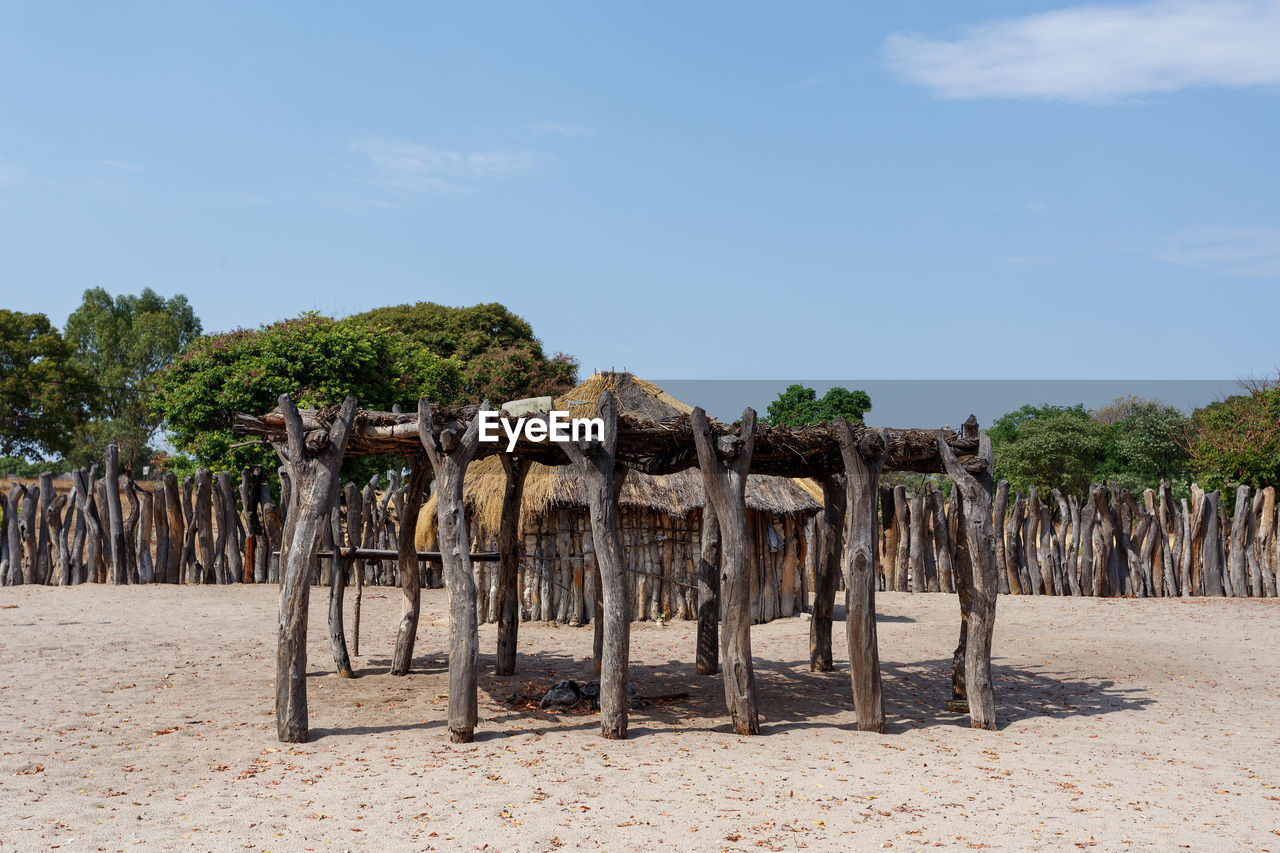 WOODEN POSTS ON BEACH AGAINST SKY