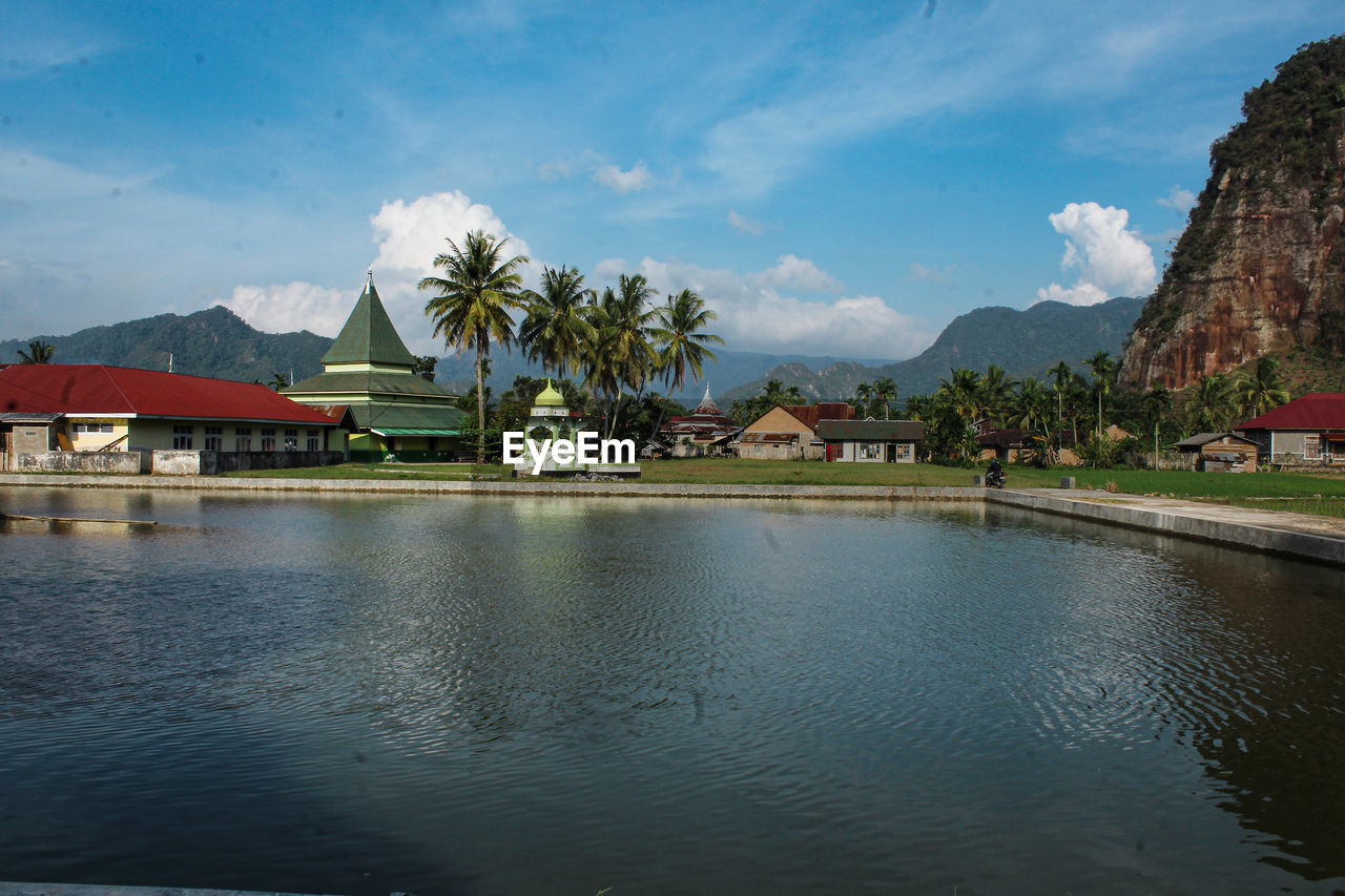 Houses by swimming pool by lake against sky