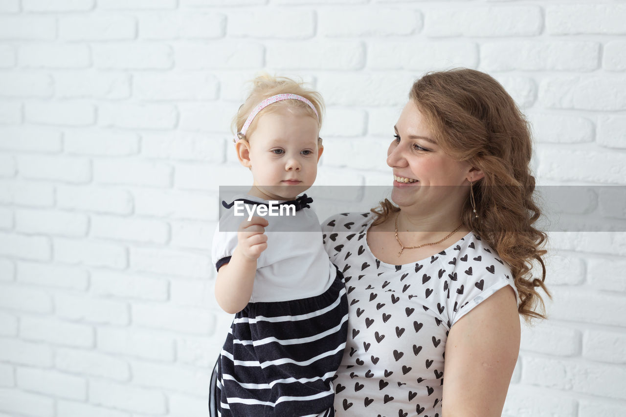 Mother with daughter against wall