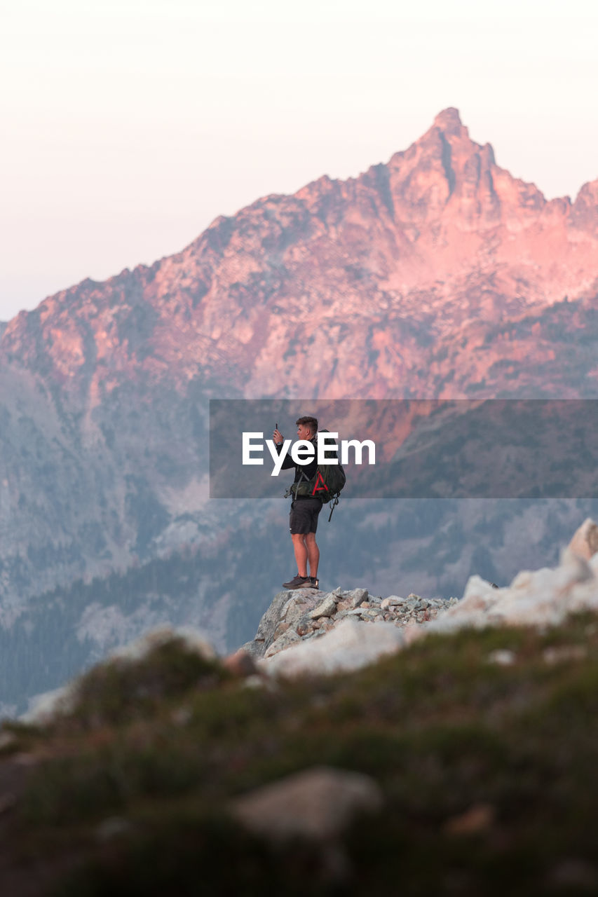 Full length of man standing on rock in mountains against sky