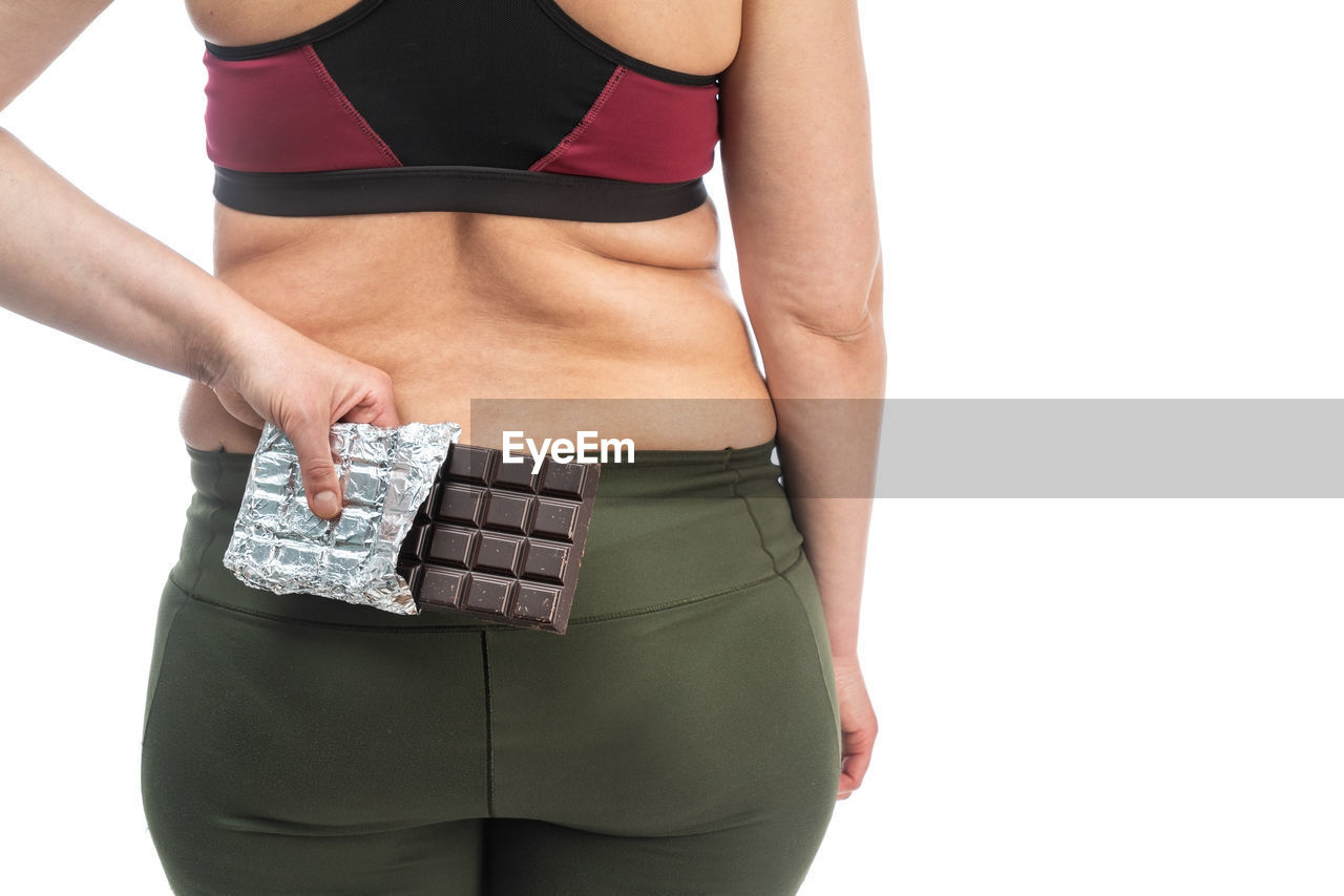 MIDSECTION OF WOMAN STANDING AGAINST GRAY BACKGROUND