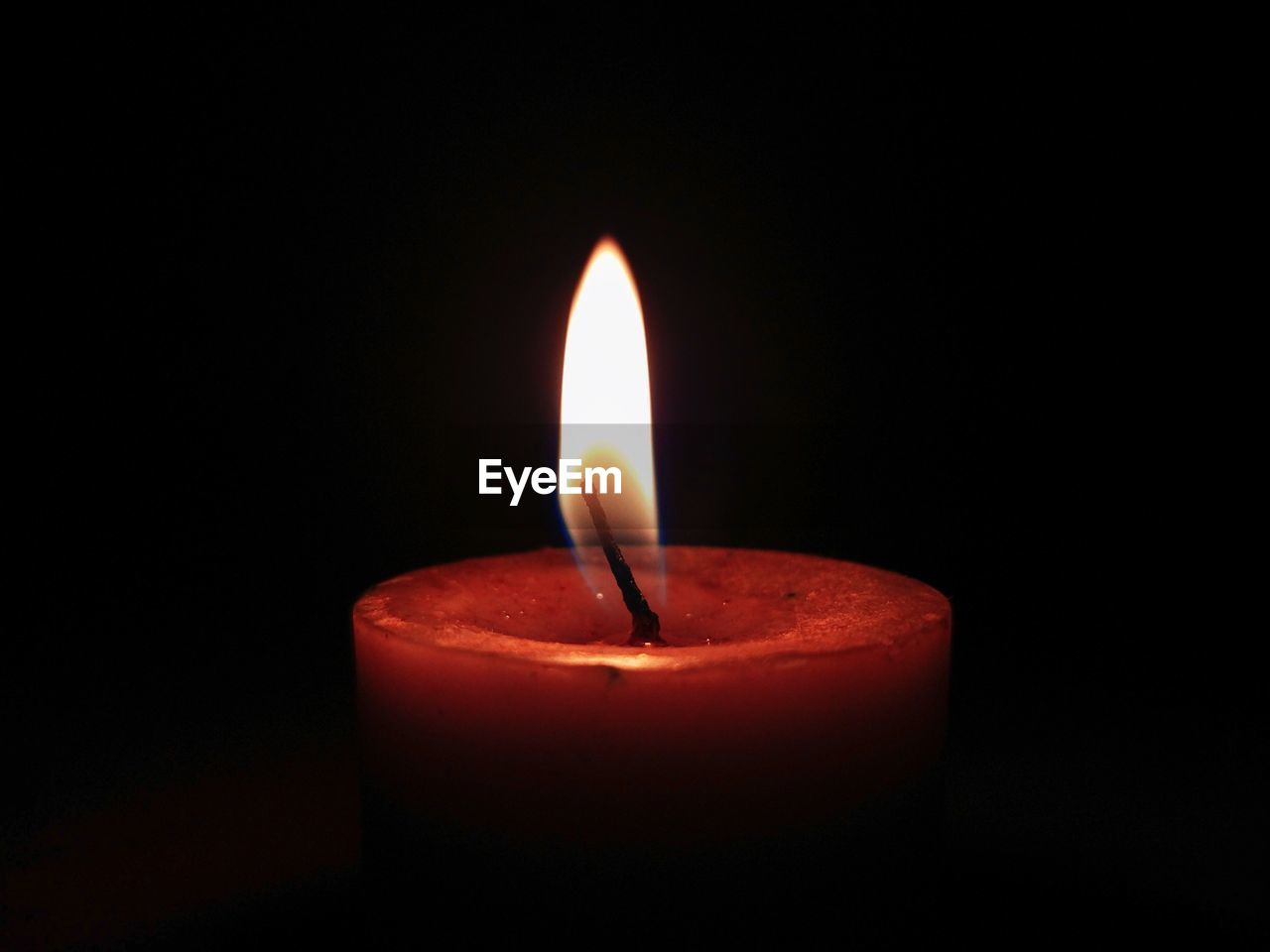 Close-up of lit candle against black background