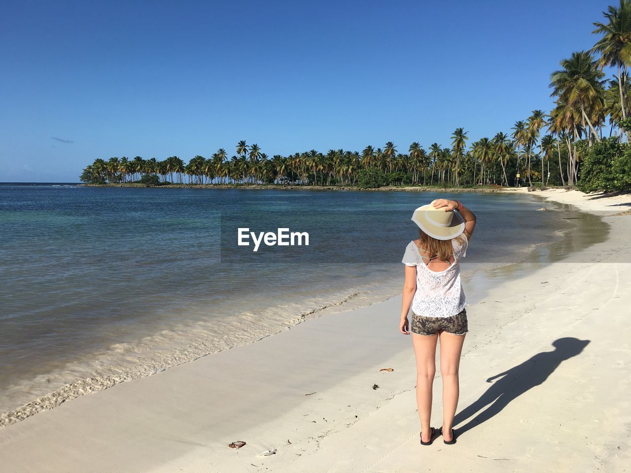 Rear view of young woman standing at beach