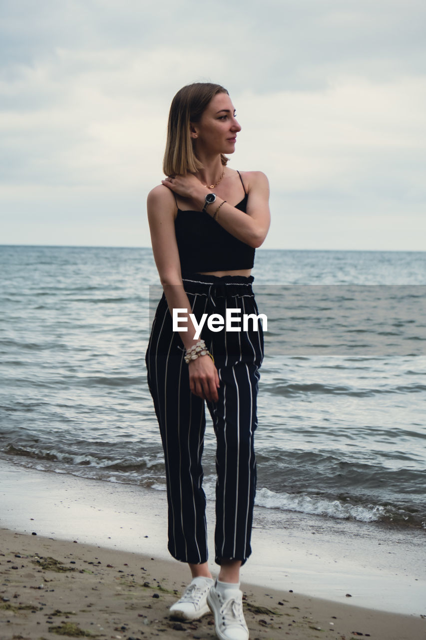 Young woman standing on blurred beachside background. attractive female enjoying walking the sea