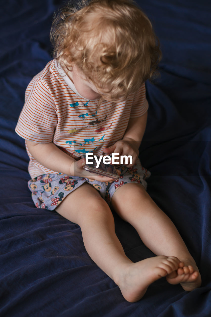 Baby girl with curly hair uses a smartphone