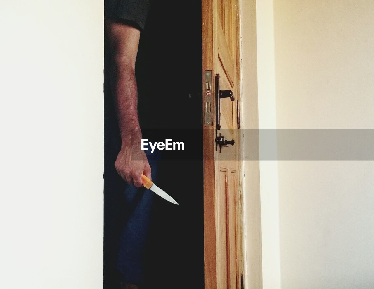 Midsection of man holding knife while standing at doorway