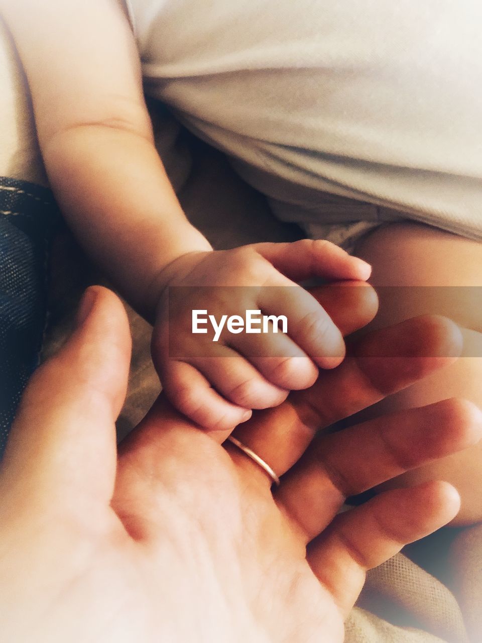 Close-up of baby holding finger of mother