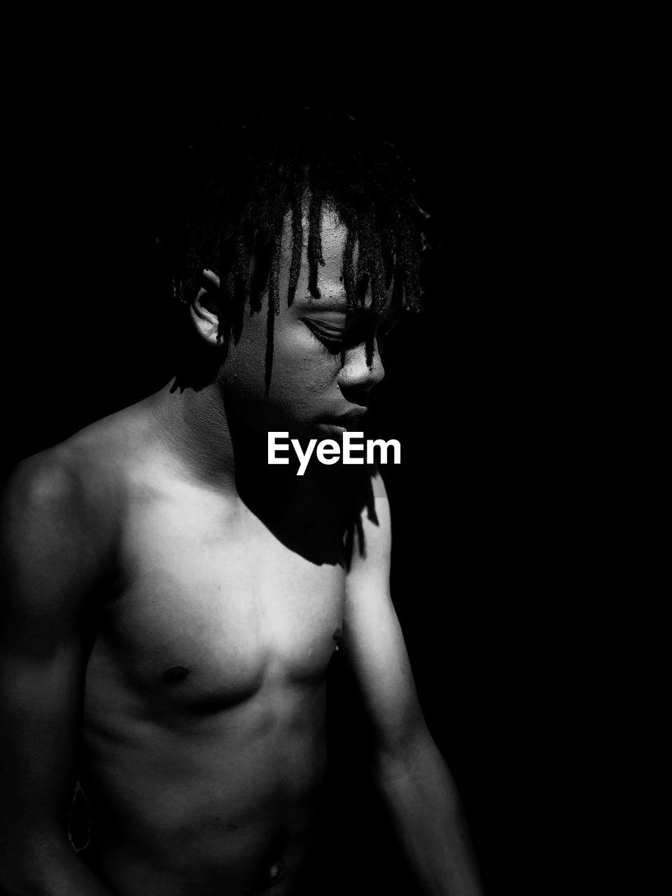 Shirtless boy against black background