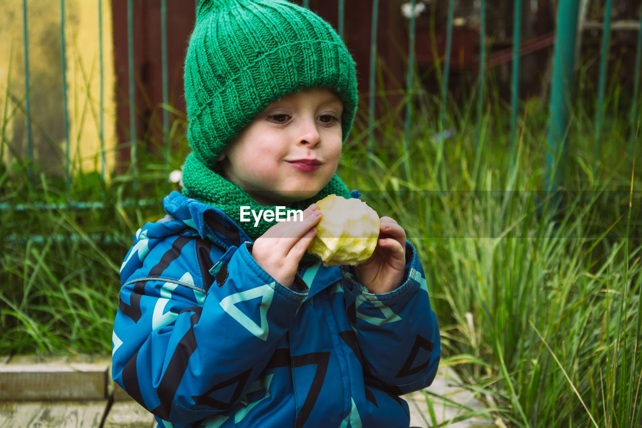 Child eating delicious apple outdoors, fruit snack. healthy food concept