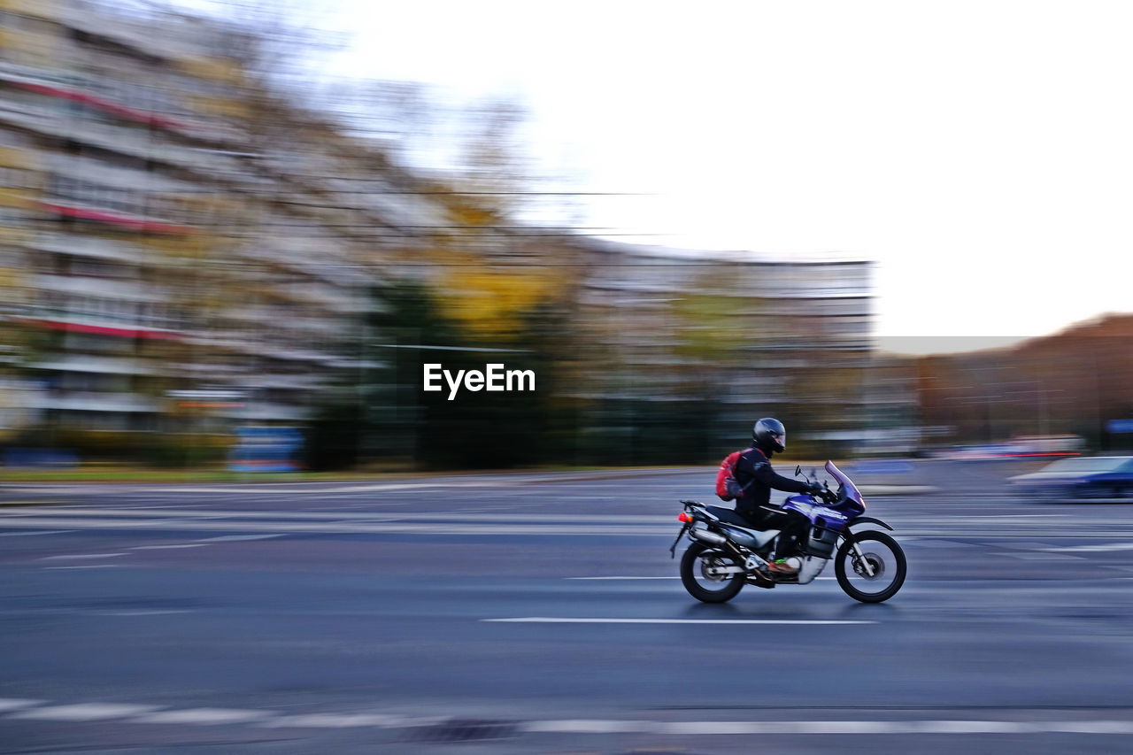 Side view of man riding motorcycle on road