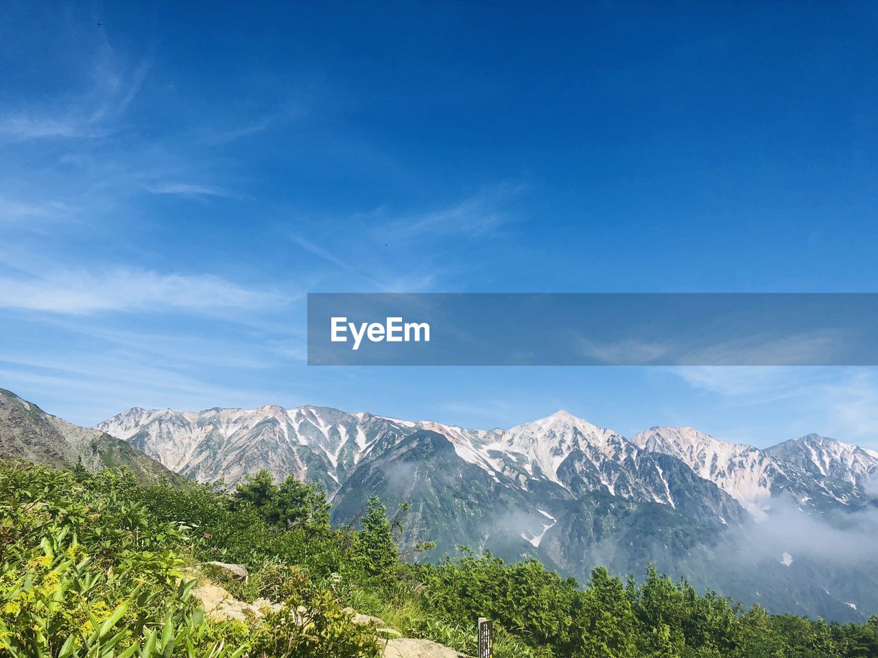 Scenic view of snowcapped mountains against blue sky