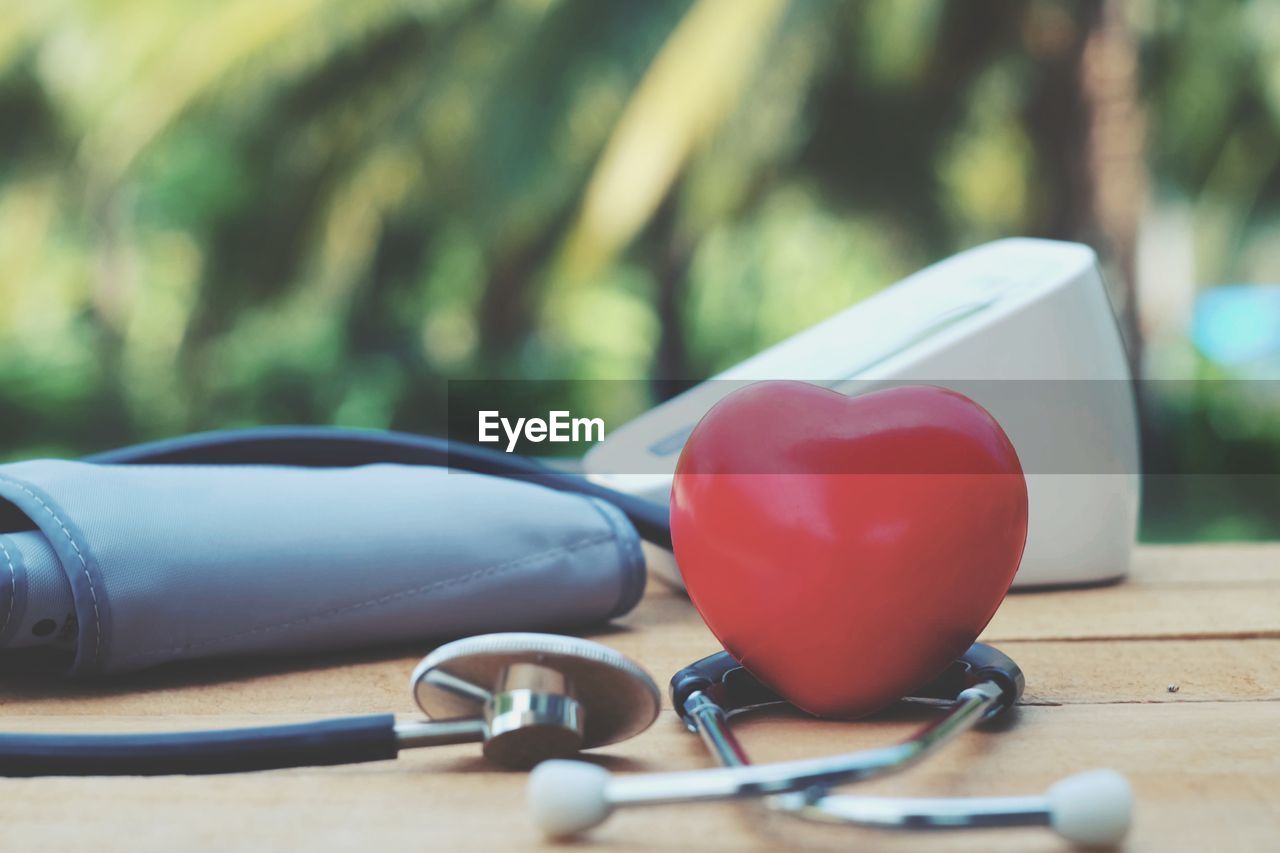 Close-up of stethoscope and heart shape on table