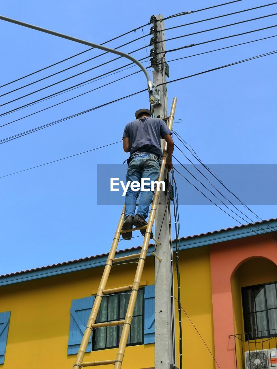 LOW ANGLE VIEW OF MAN WORKING AGAINST SKY