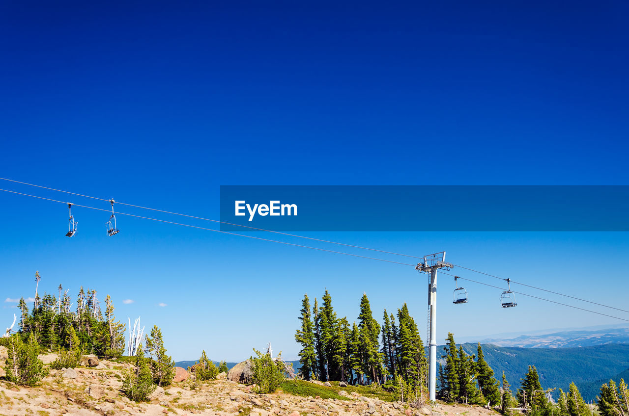 Low angle view of ski lift against clear blue sky
