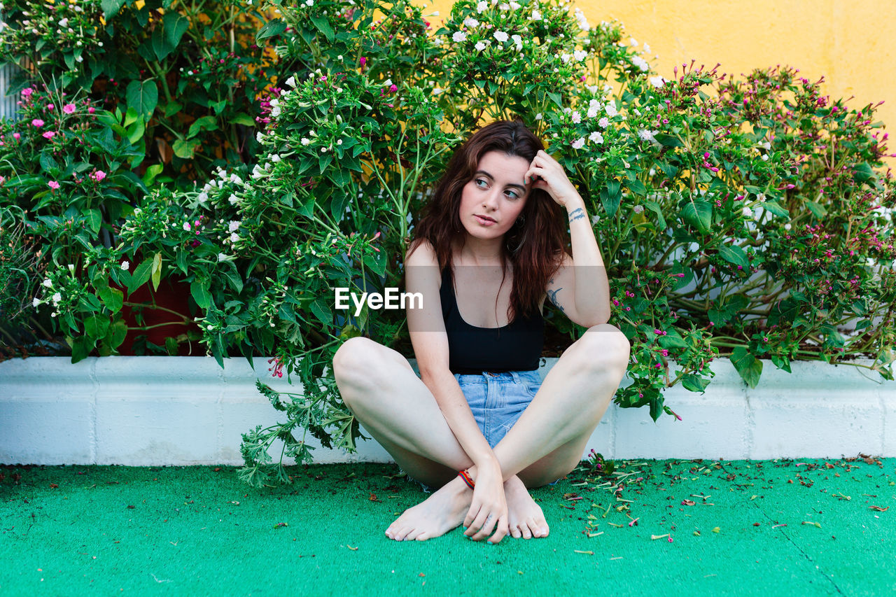 Thoughtful woman sitting alone outdoors. young worried in backyard