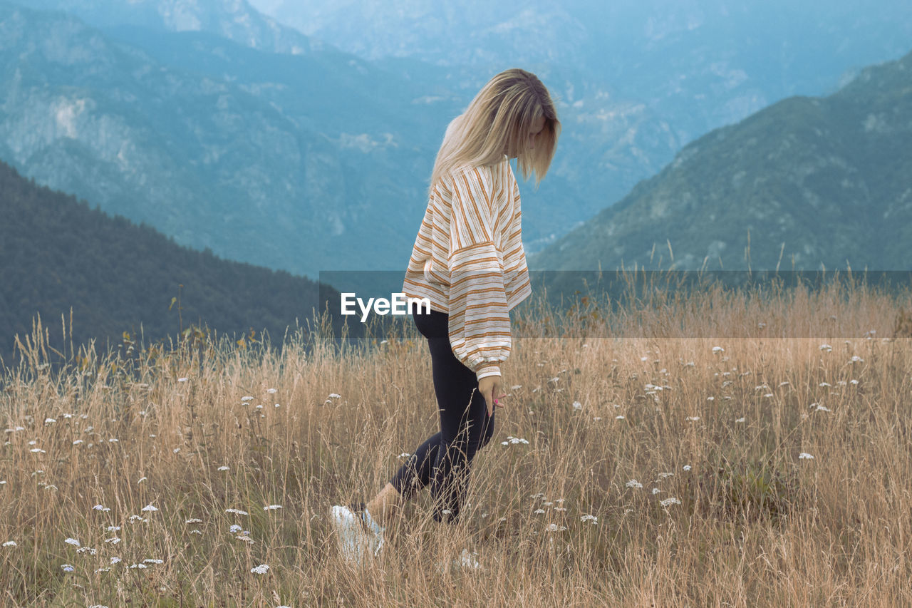 Side view of woman standing on grassy mountain