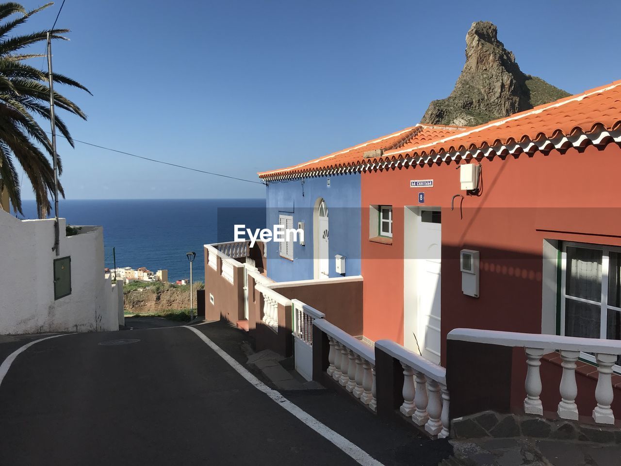 Buildings by sea against clear blue sky