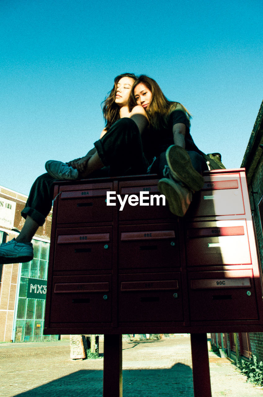 Portrait of women sitting on postbox