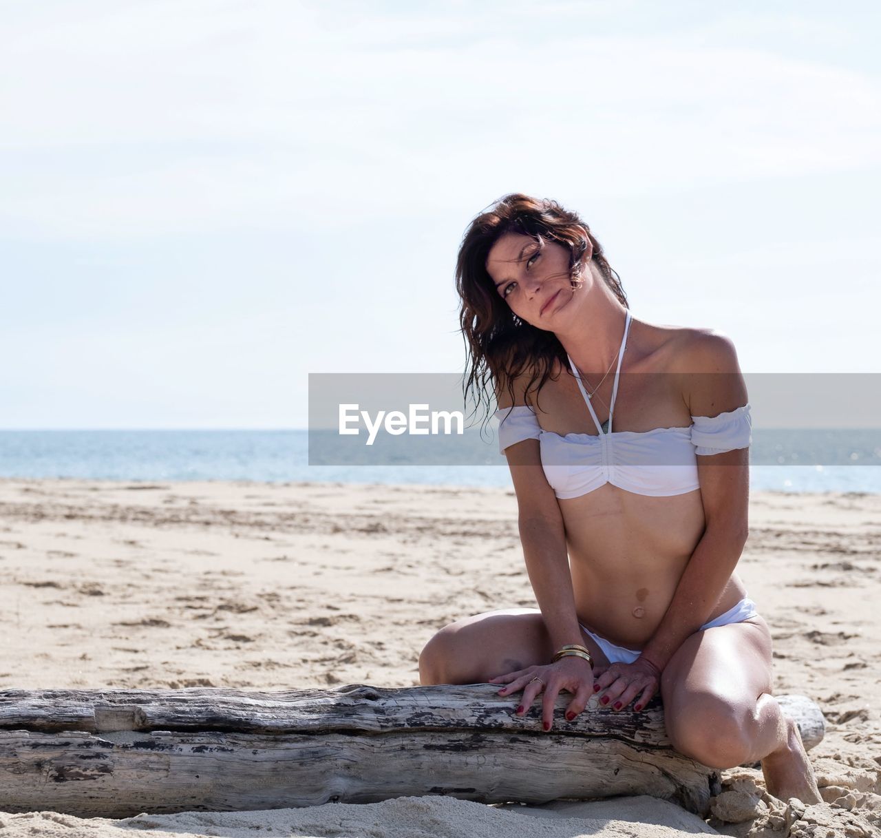 beach, land, one person, adult, water, sea, clothing, women, young adult, leisure activity, nature, holiday, bikini, vacation, trip, relaxation, full length, summer, human leg, female, sky, hairstyle, sand, photo shoot, limb, lifestyles, swimwear, sitting, sun tanning, day, long hair, person, fashion, body of water, outdoors, sunlight, glasses, brown hair, beauty in nature, front view, horizon over water, horizon, looking, emotion, smiling, sunglasses, copy space, portrait, travel, tranquility, shore, happiness, casual clothing