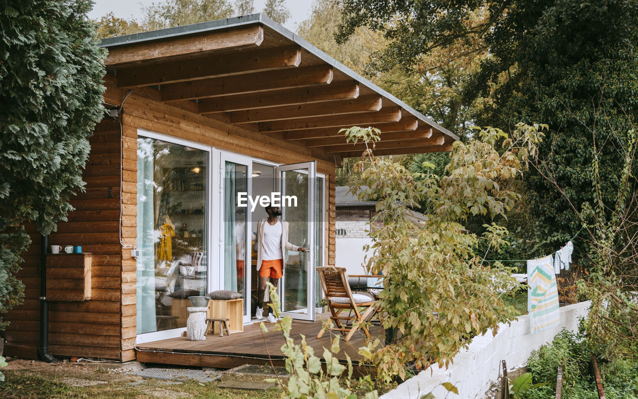 Mature man standing at doorway of tiny house