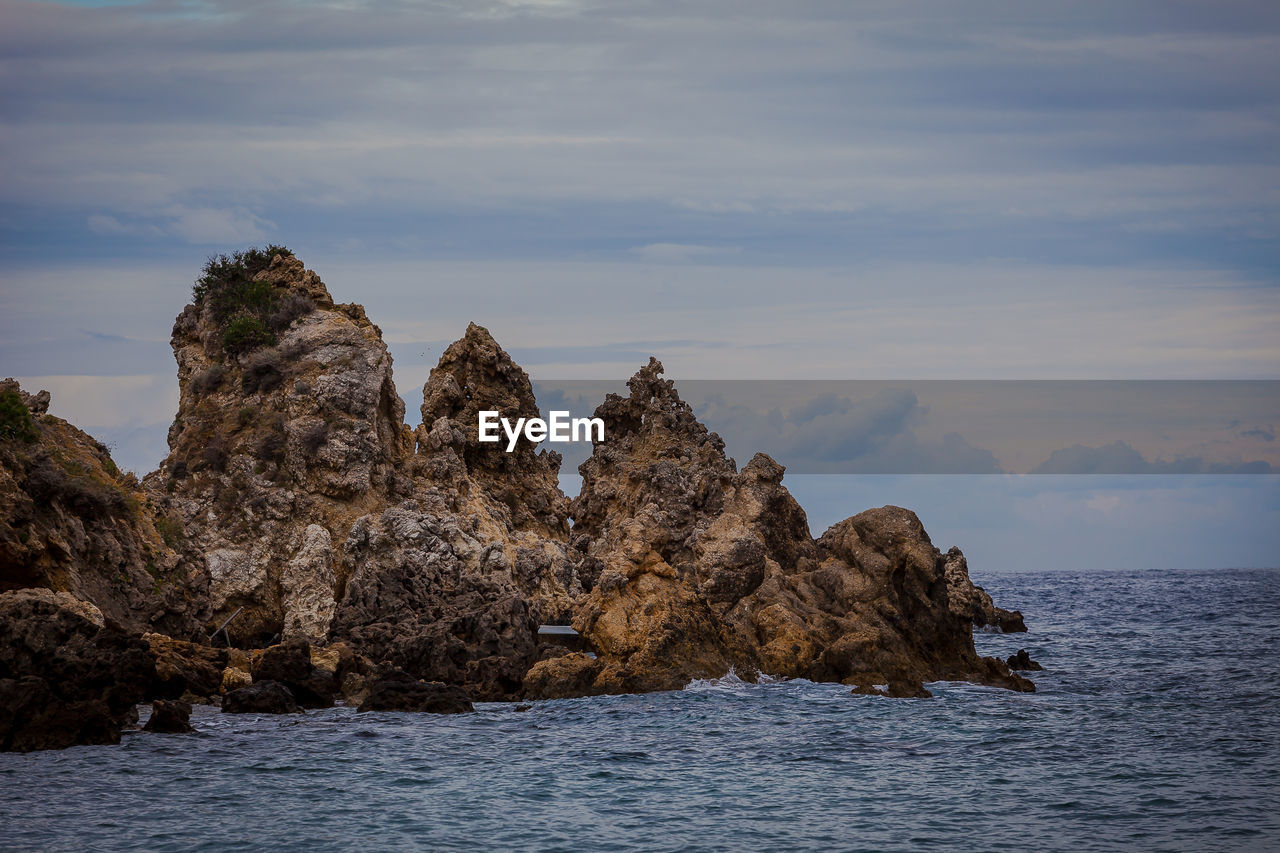 Rock formation in sea against sky