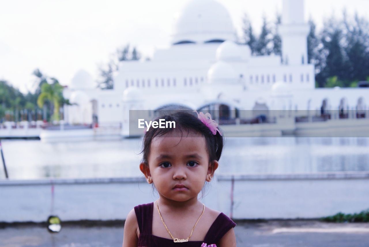 Portrait of cute girl against mosque